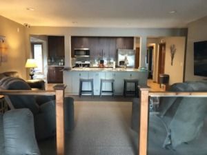 Modern living room opening to a kitchen with bar stools and warm lighting