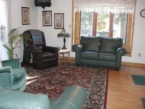 Living room with green sofa, armchair, patterned rug, lamp, and large window