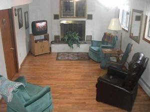 Cozy living room with teal and black chairs, a TV, fireplace, and wood floors