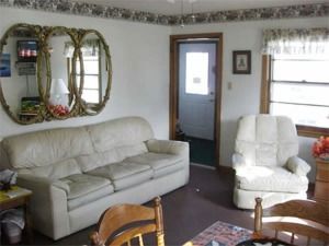 Living room with beige sofa, white armchair, and wall mirror beside a window and door