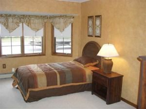 Small bedroom with a single bed, lamp on nightstand, and window with valance curtains