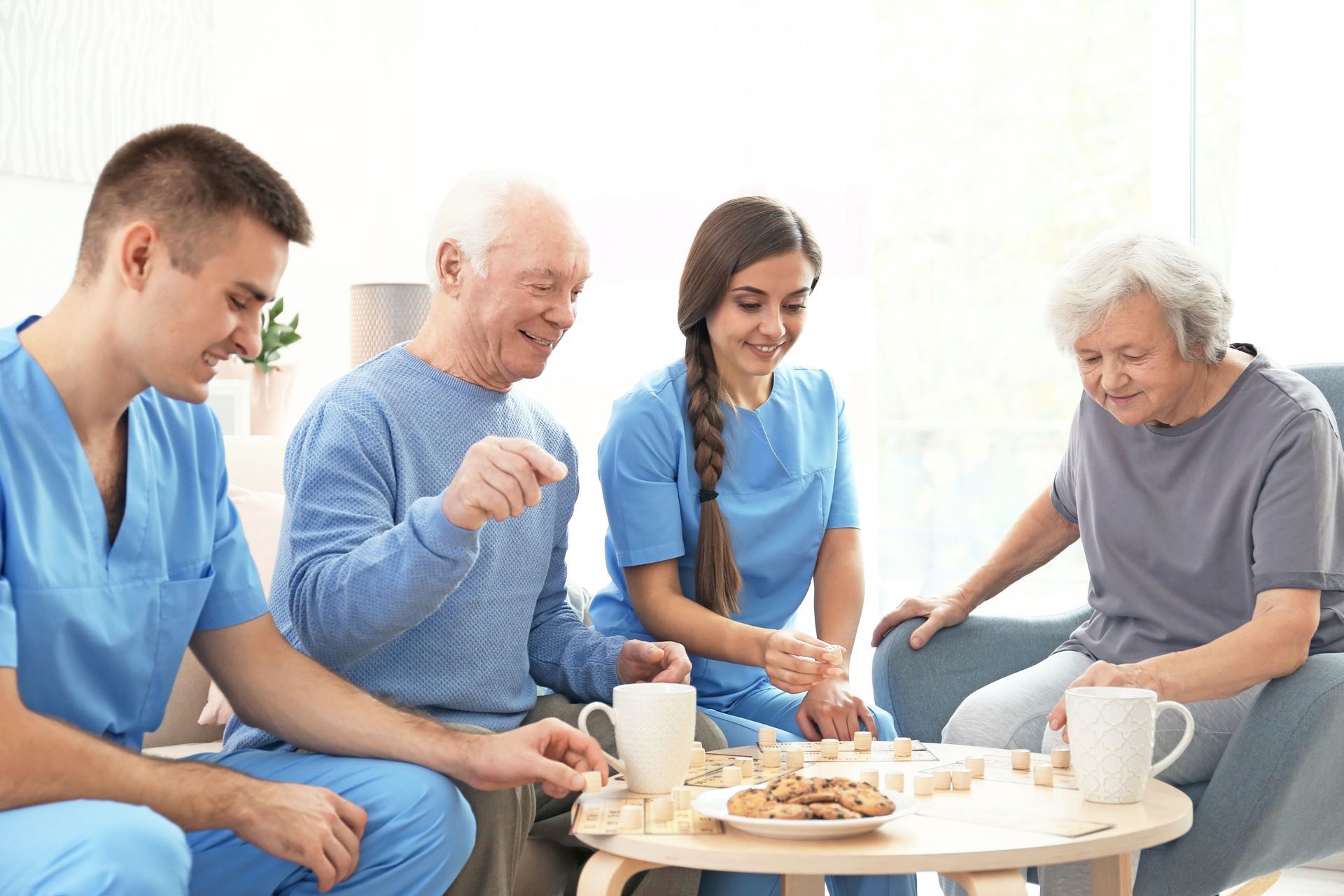 Four people share tea and pastries around a table in a bright room