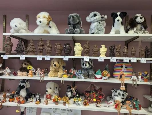 Shelves filled with stuffed dog toys and figurines, including chocolate characters, in a shop setting.