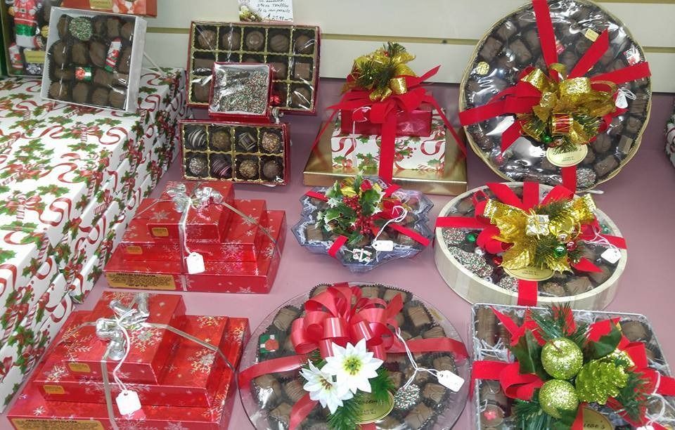 Holiday chocolates arranged as gifts, wrapped in red, with ribbons and decorative accents.