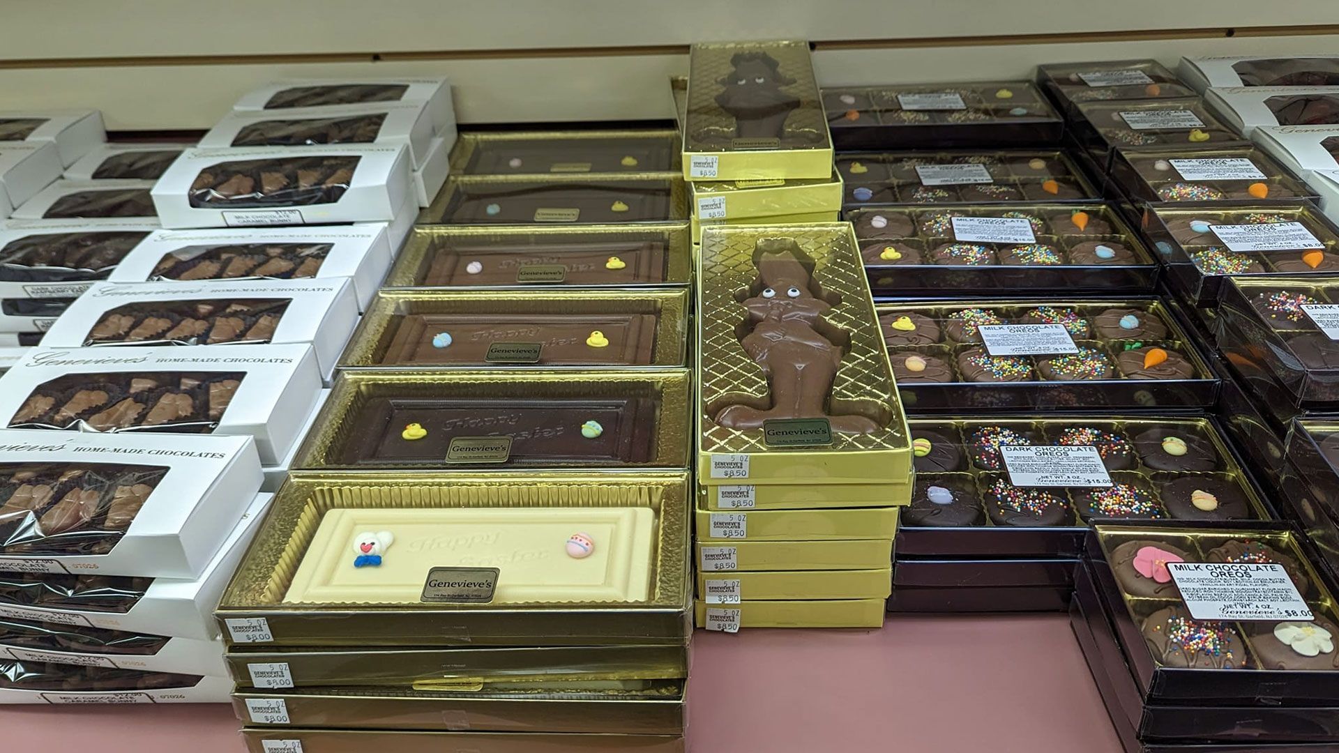 Shelves filled with boxes of chocolate treats; some white, gold, and dark brown boxes.