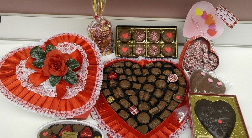 Valentine's Day chocolates: heart-shaped boxes and treats in red, white, and brown on a white surface.