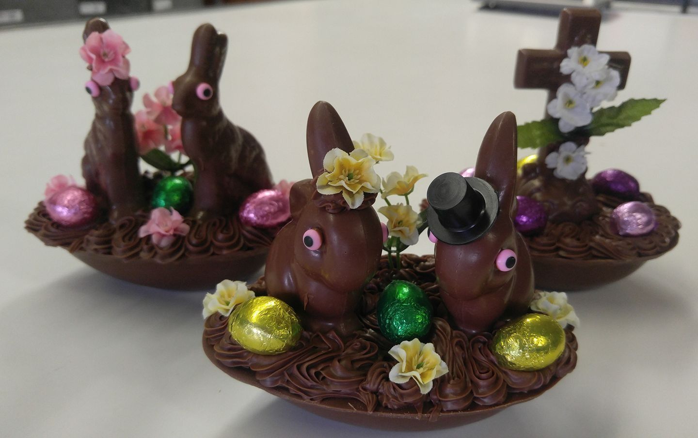 Three chocolate Easter bunny scenes with eggs and flowers.