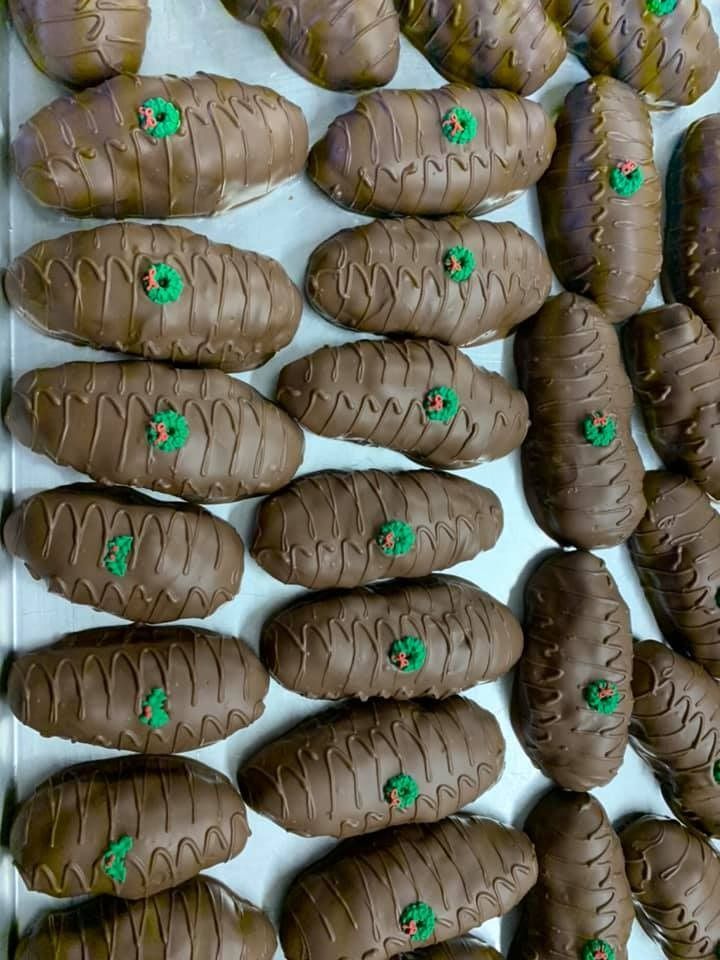 Tray of oblong, chocolate-covered pastries, decorated with brown icing lines and small green accents.