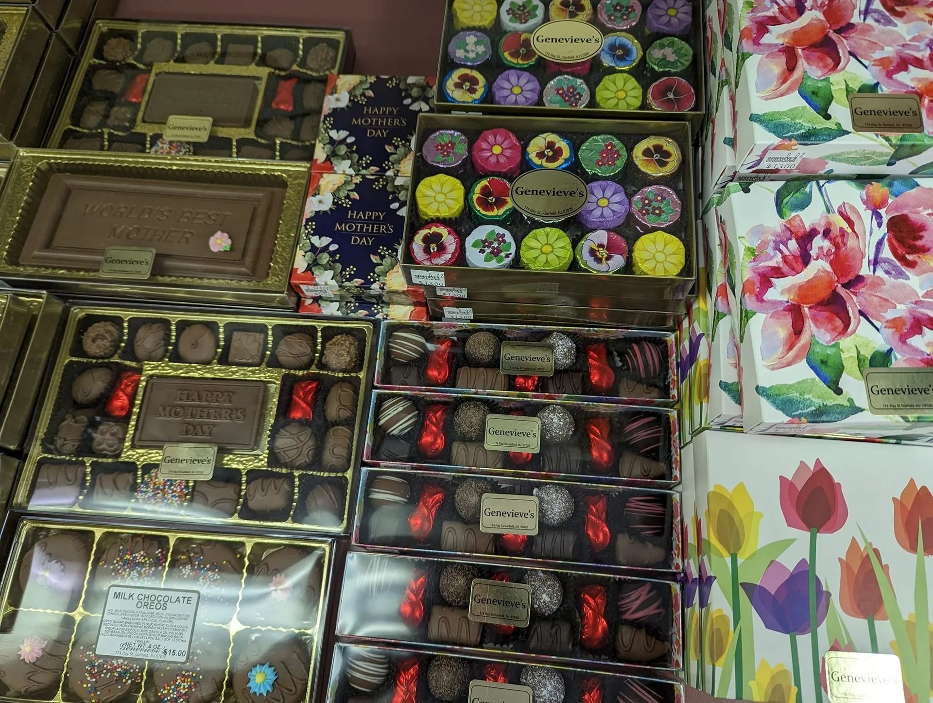 Shelves filled with boxes of chocolates, various shapes and designs, including floral prints and gold accents.