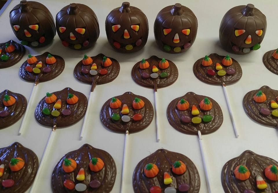 Chocolate pumpkin treats decorated with candy on a white surface.
