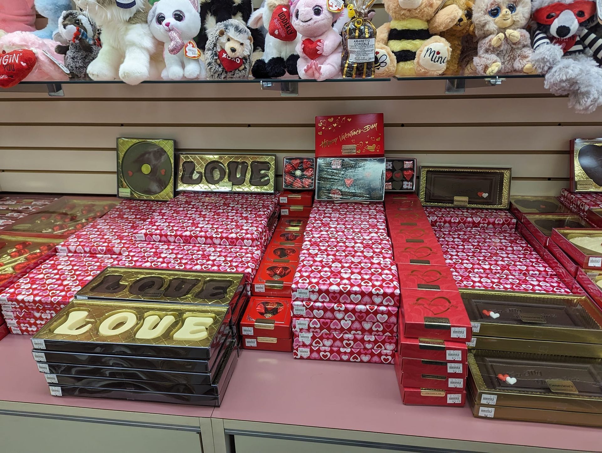 Shelves displaying Valentine's Day chocolates in red and gold boxes with