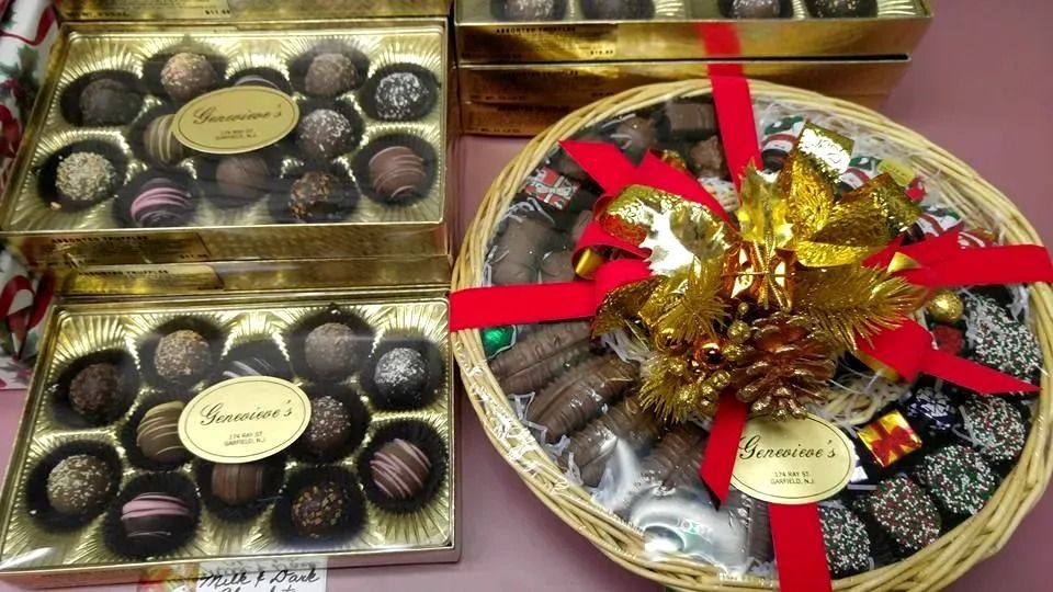 Boxes and basket of assorted chocolates, gold ribbon and decorations.