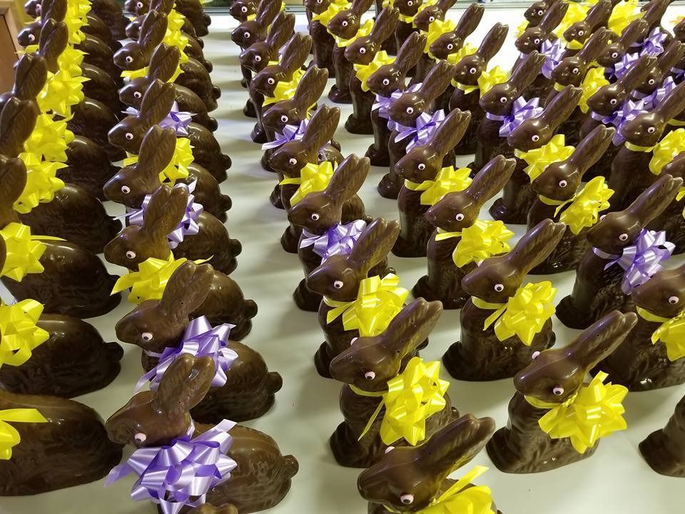 Rows of chocolate bunnies with yellow and purple bows, ready for Easter.