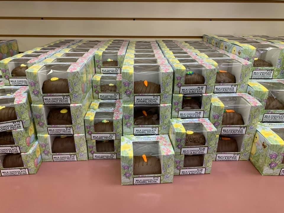 Rows of boxes containing a brown loaf with a small carrot, arranged on a pink surface.