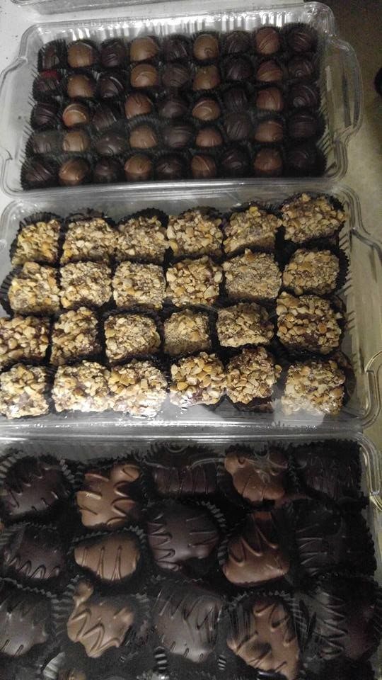 Three trays of assorted chocolates: truffles, nut-covered, and filled shapes.