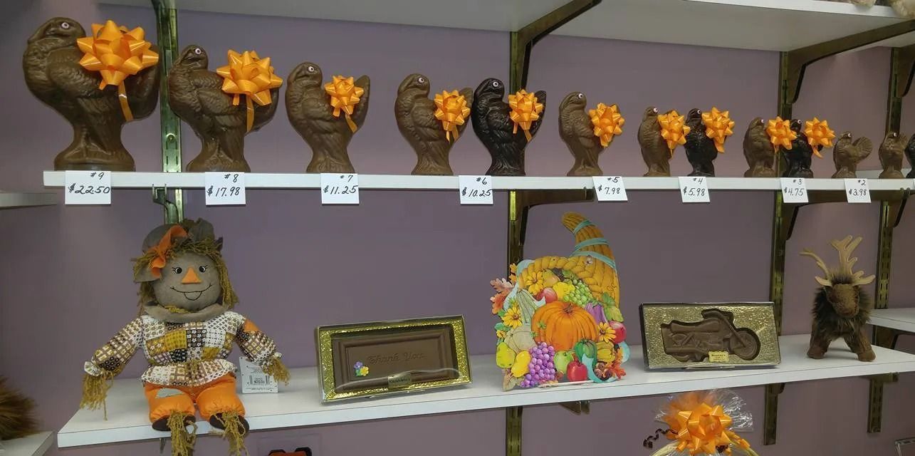 Shelves of turkey-shaped chocolates with orange bows, decorative crafts, and a scarecrow doll.