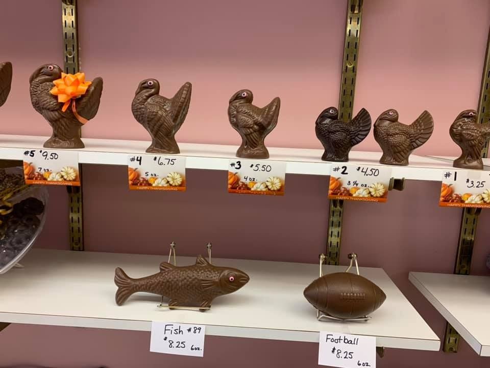 Chocolate chickens, fish, and football on shelves in a shop, all priced.