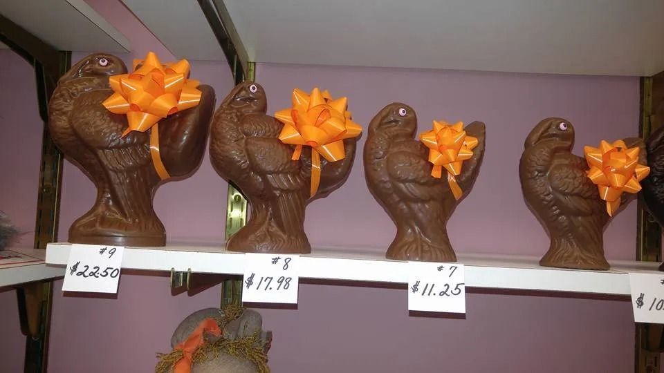 Four chocolate dove figurines with orange bows on a shelf, with price tags.