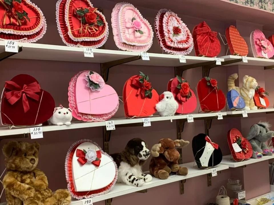 Shelves display heart-shaped Valentine's Day candy boxes and stuffed animals; pink and red color scheme.