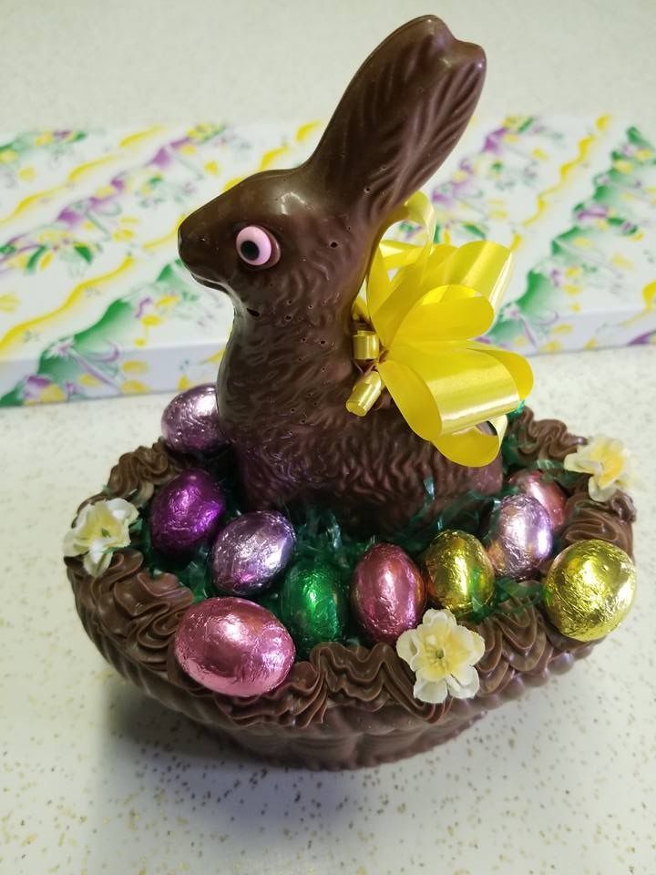 Chocolate bunny in a basket with foil-wrapped eggs and yellow bow.