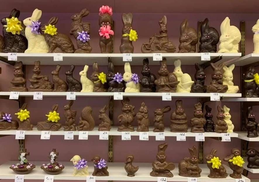 Shelves filled with various chocolate Easter bunnies and figurines, many adorned with small colorful ribbons.