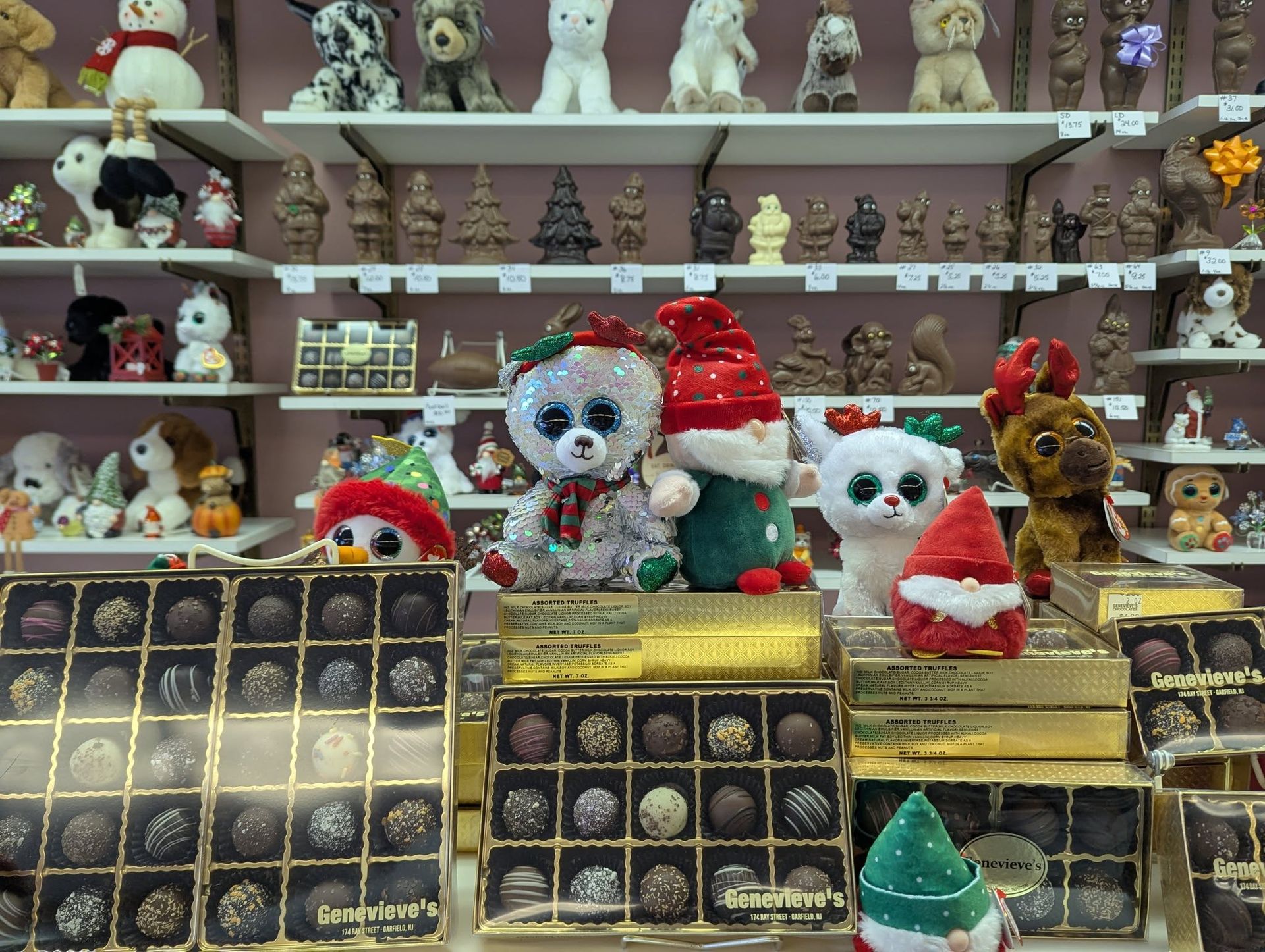 Shelves of chocolates and figurines, including animals, on display in a shop. Holiday decorations are present.