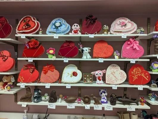 Shelves filled with heart-shaped candy boxes and chocolate figurines in a store.