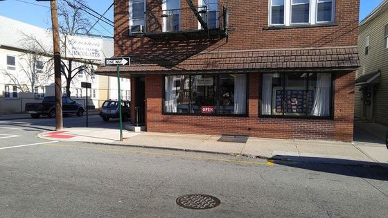 Brick building with storefront windows at a street corner. "One Way" sign visible.