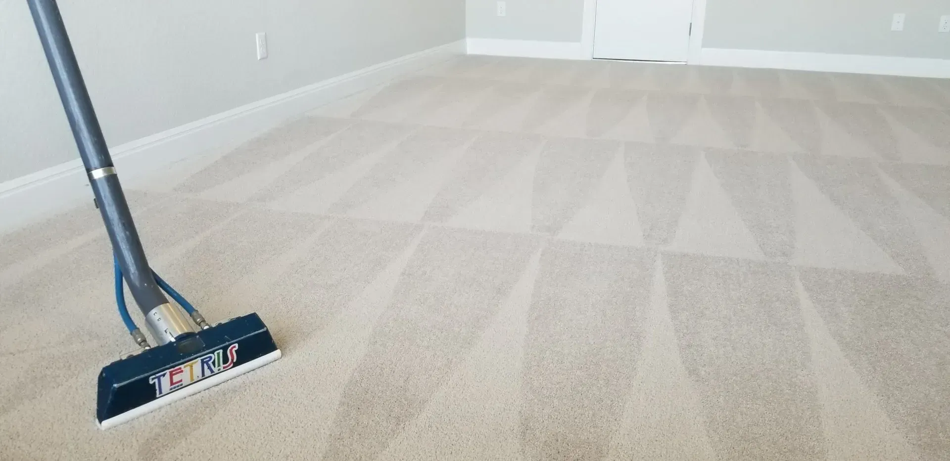 Vacuum cleaner on beige carpet in a sparsely furnished room