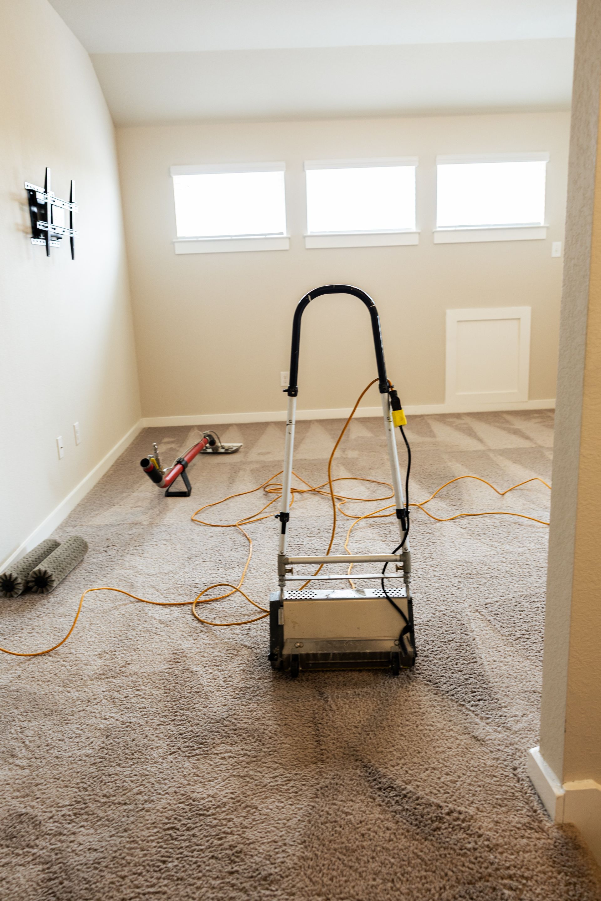 Carpet cleaning machine in a beige room with fresh foam and cleaning tools on the floor.