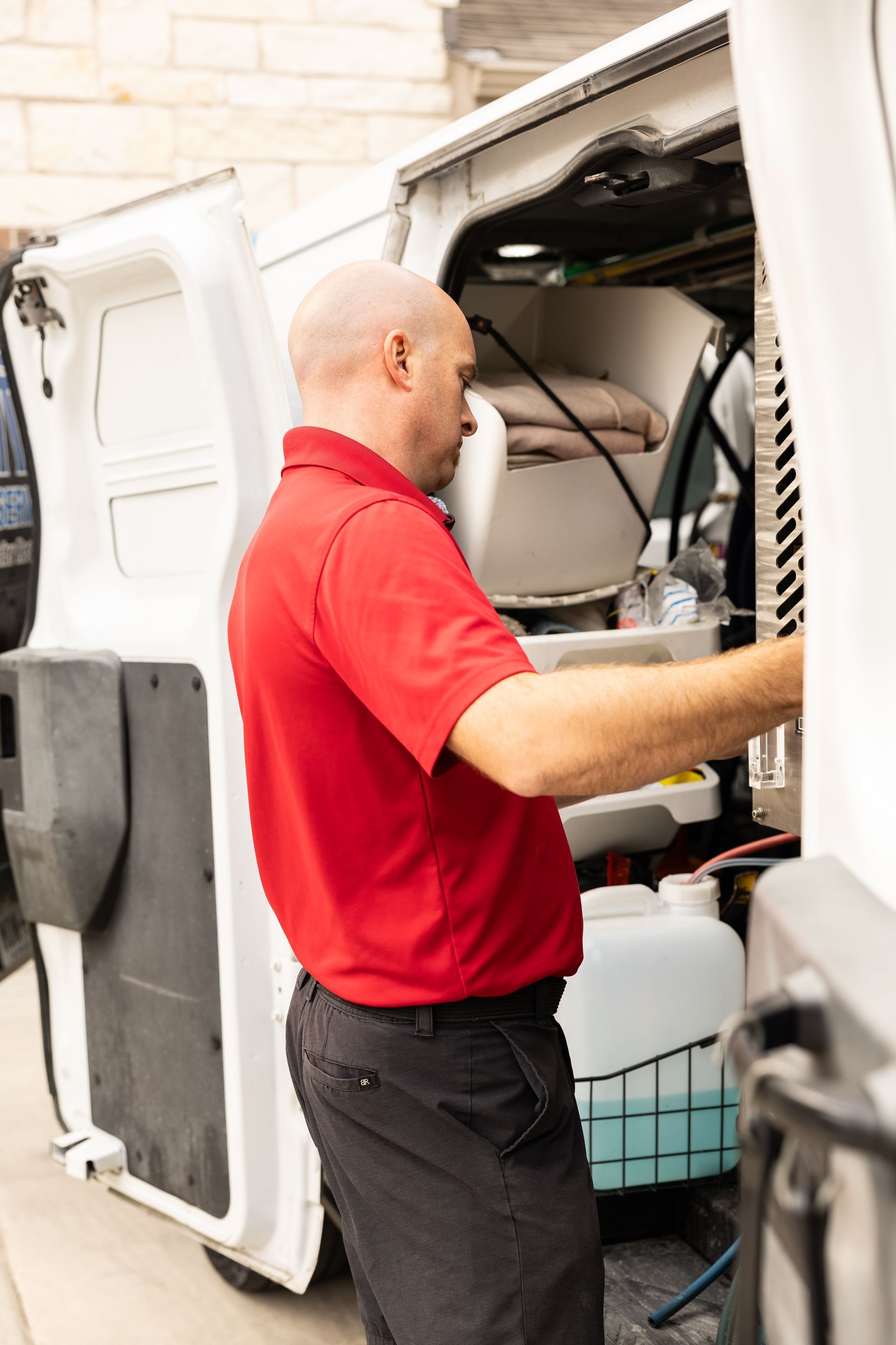 Technician in a red shirt working on equipment inside a white utility van