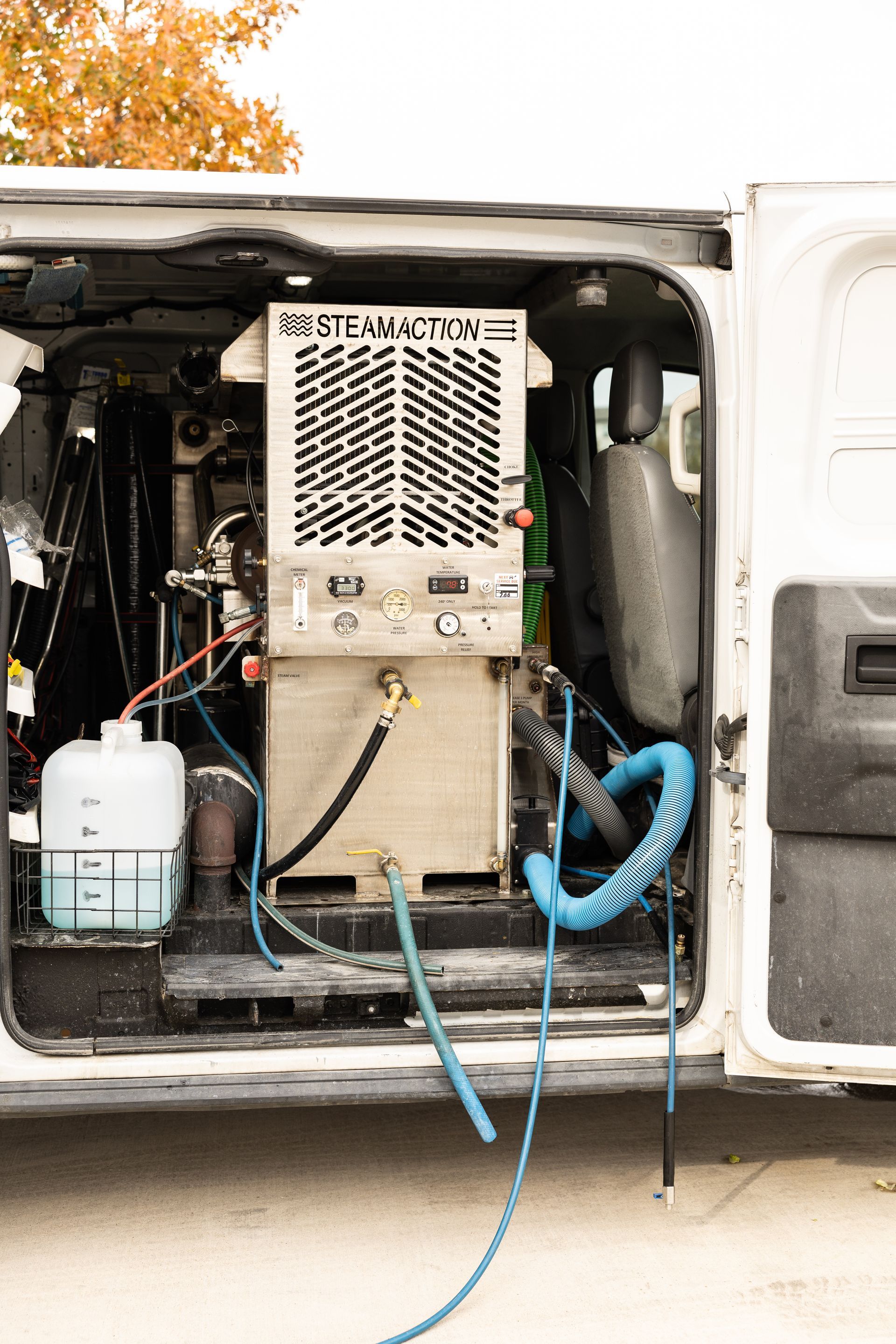 Open utility cabinet with electrical equipment, cables, and blue hose mounted on a vehicle or trailer