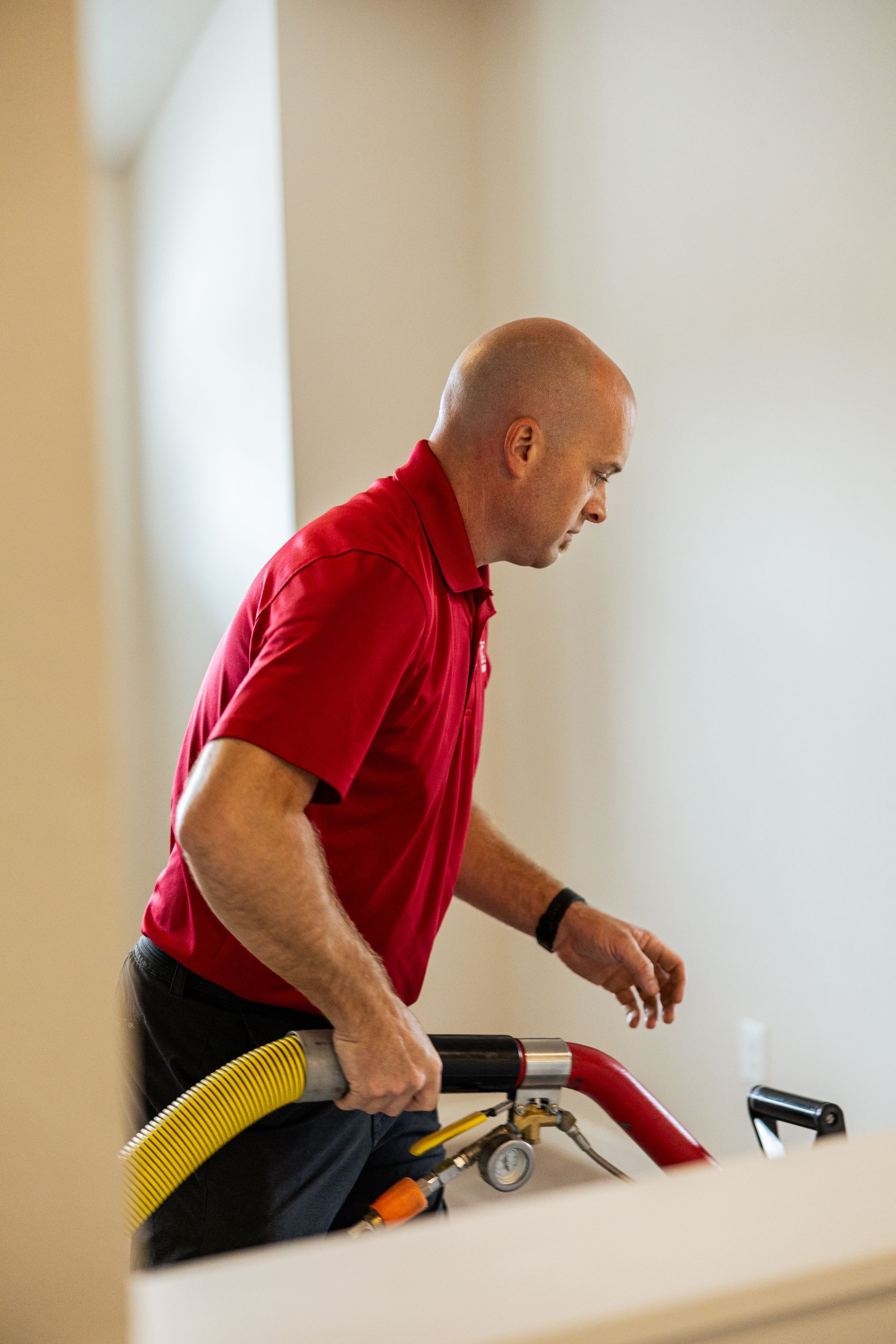 Man in a red shirt leaning over a treadmill indoors