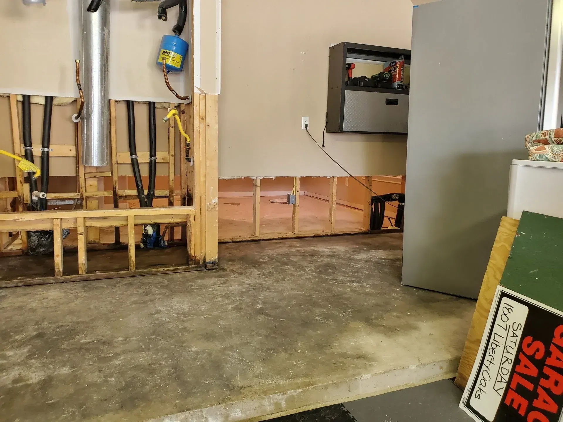Garage interior with exposed framing, tools, and a tiled floor under construction