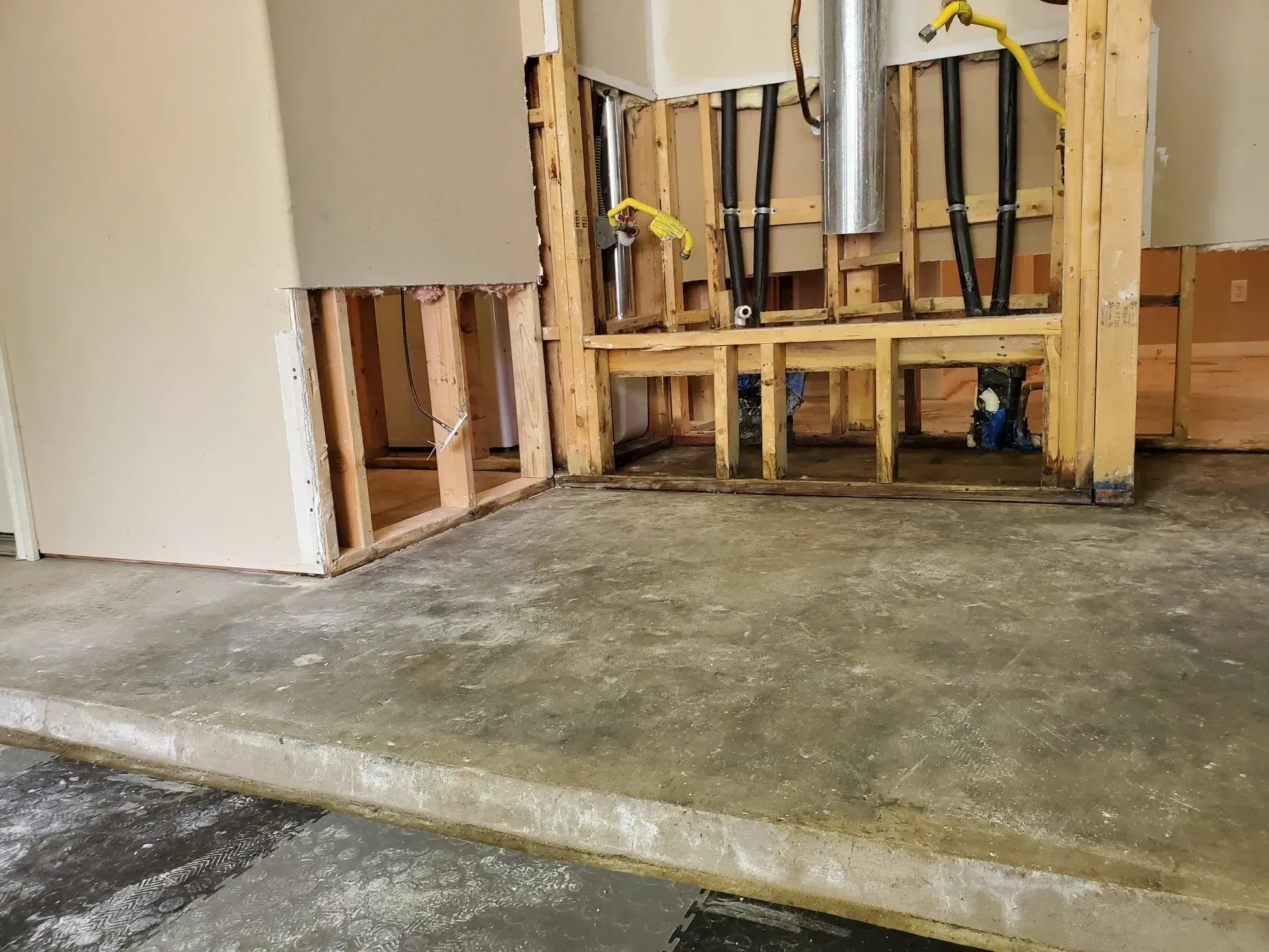Partially renovated room with exposed wall framing and a concrete floor