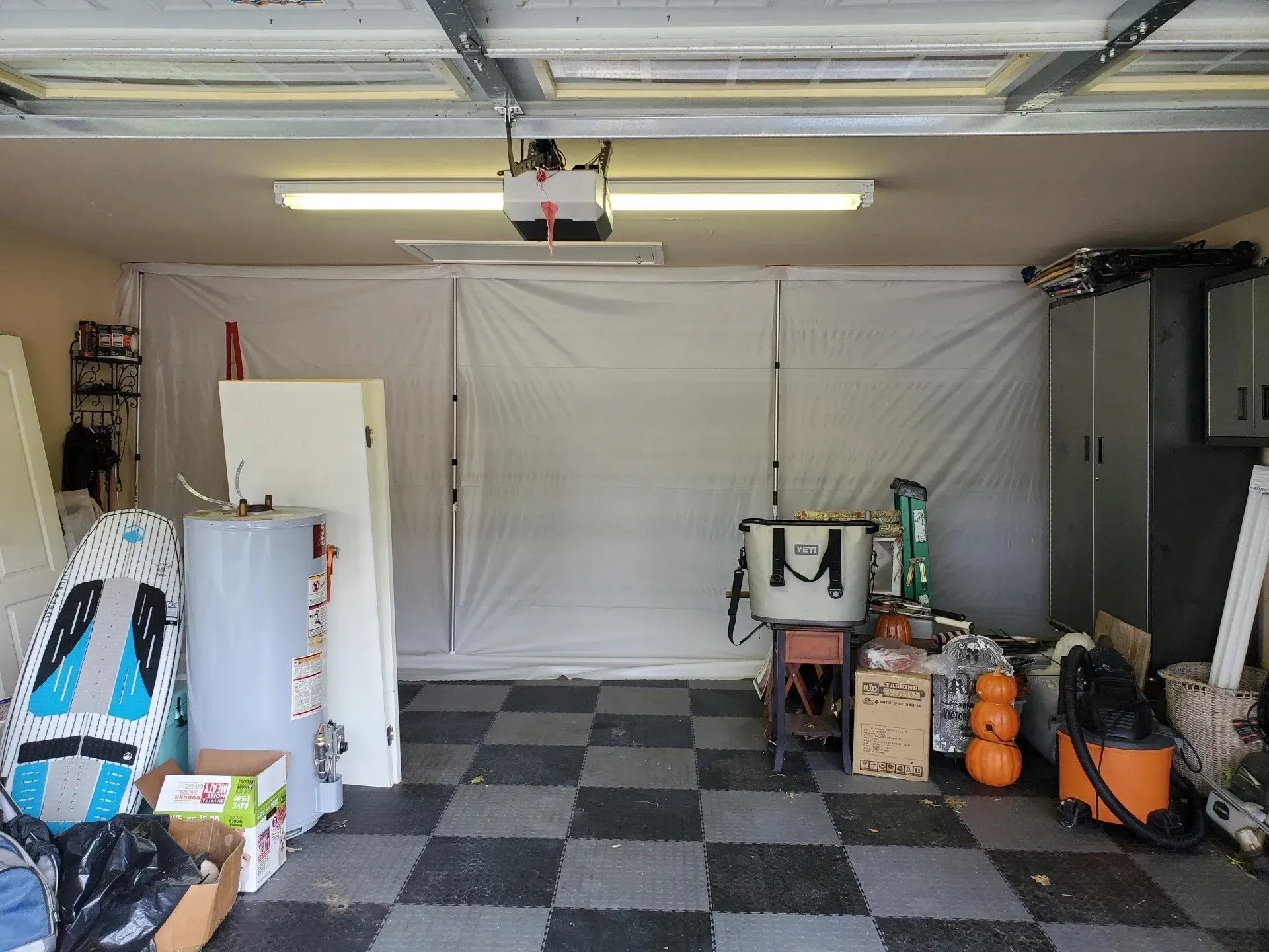 Garage interior with checkered floor, tools, storage shelves, and a closed white door cover