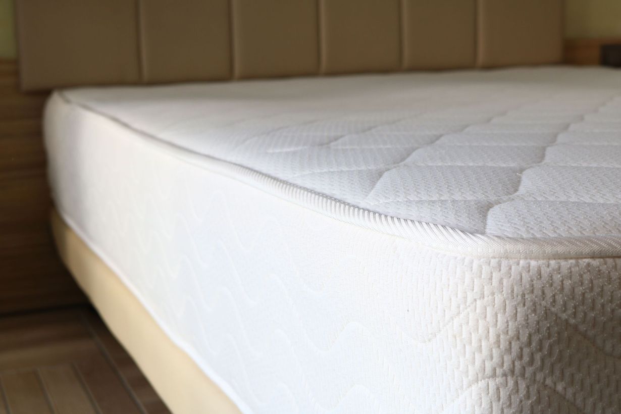 White mattress with quilted top on a wooden bed frame in a bedroom