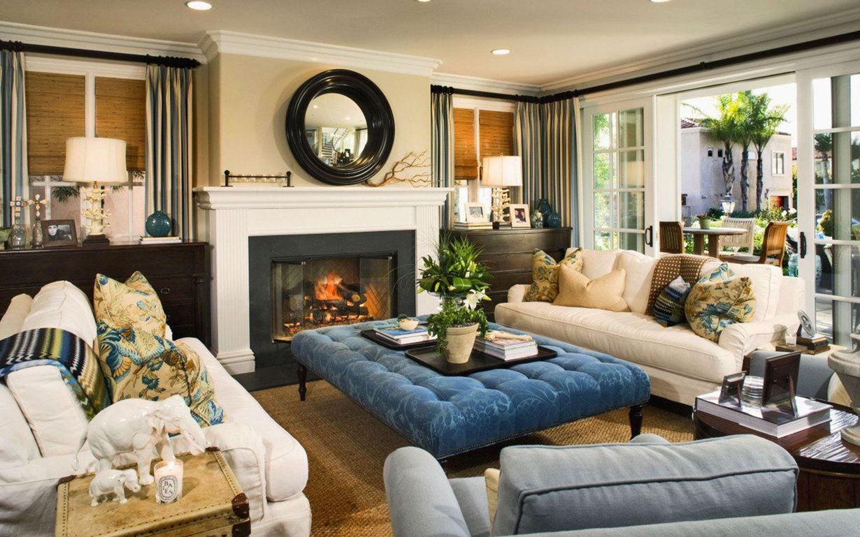 Cozy living room with white sofas, blue ottoman, fireplace, and large windows with garden view
