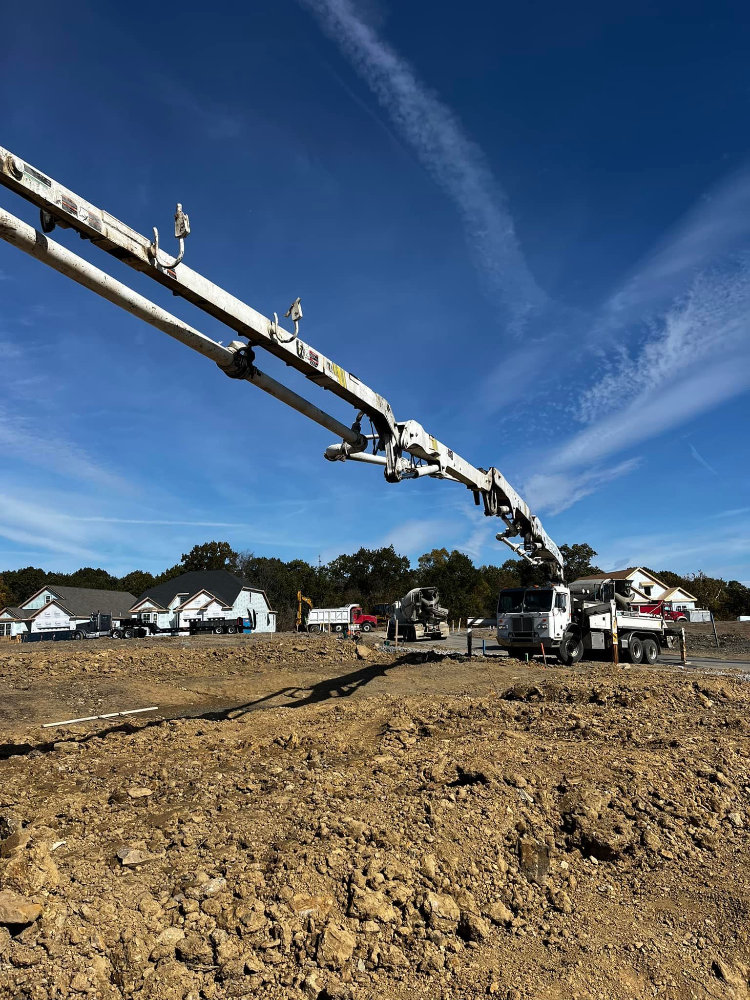 Concrete pump truck pouring concrete at a construction site on a sunny day.