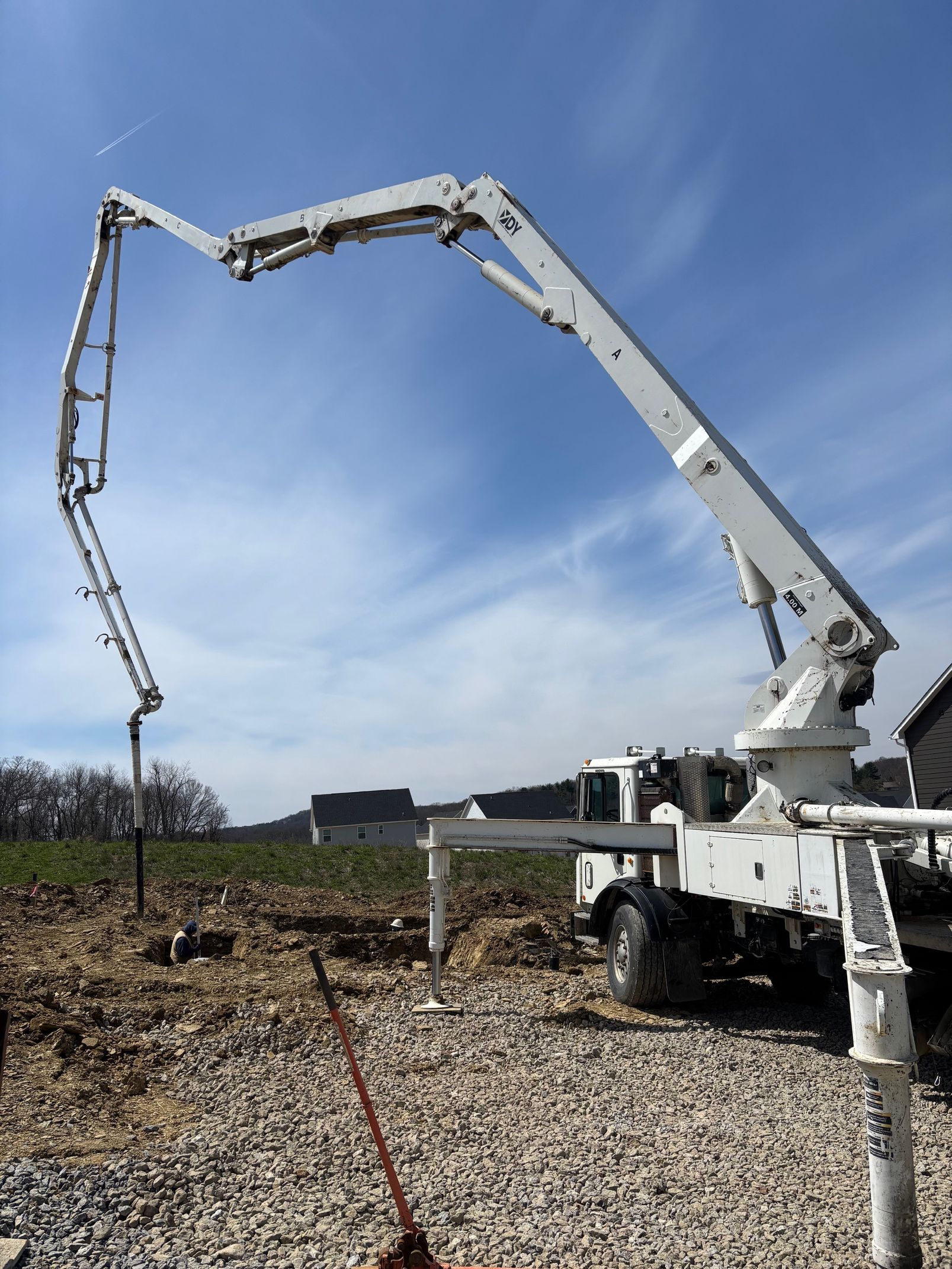 Concrete pump truck with extended boom, outdoors under a blue sky.