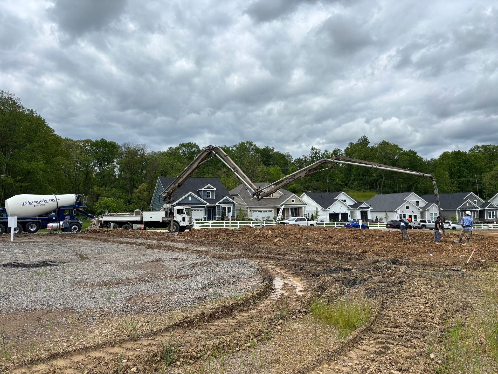 Construction site with concrete pump truck pouring concrete for house foundation on a cloudy day.