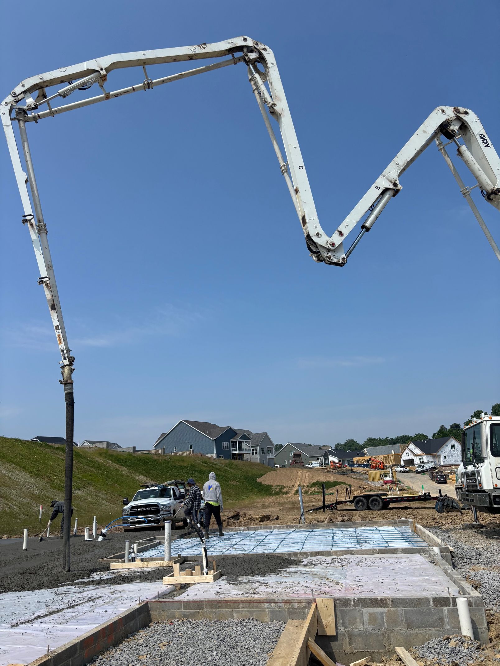 Concrete being poured at a construction site by a boom pump on a sunny day.