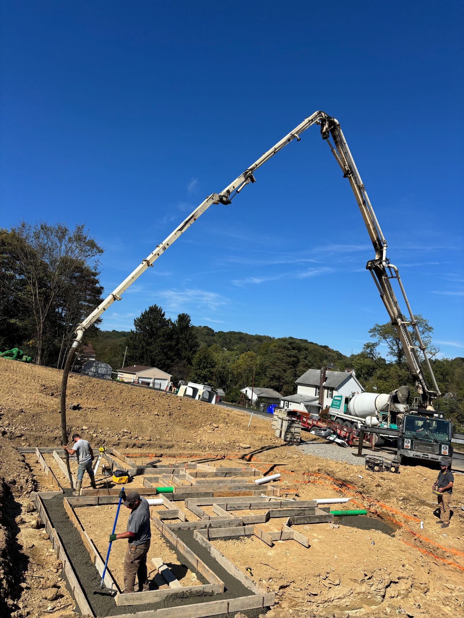 Concrete being poured into foundation forms by a pump, construction site.