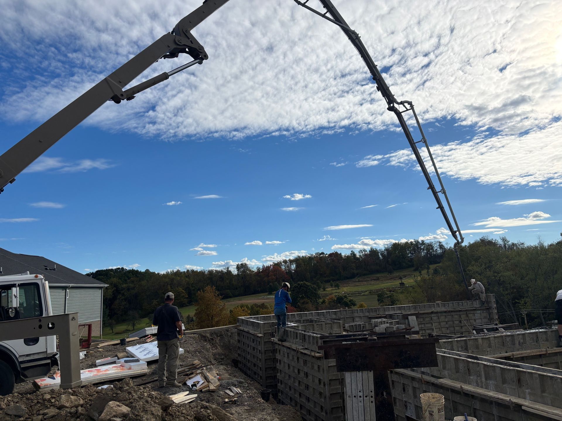 Concrete being poured into forms on a construction site; workers, blue sky, concrete pump.