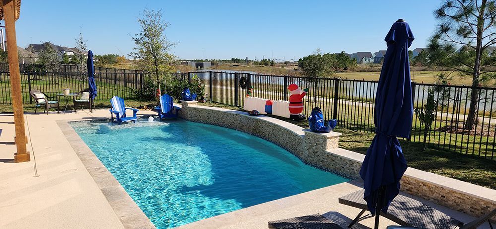A large swimming pool with chairs and umbrellas in a backyard.