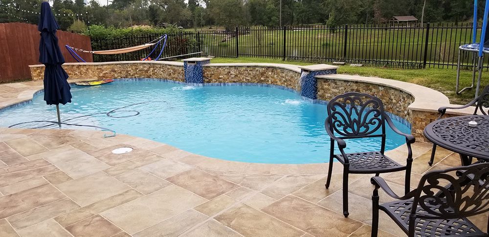 A large swimming pool with a table and chairs around it.