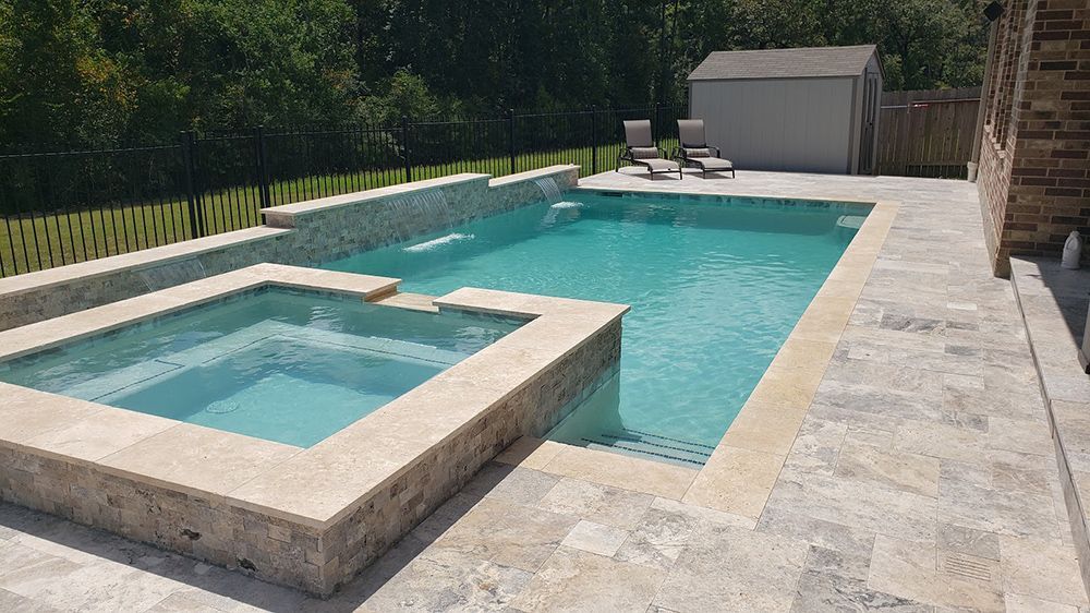A large swimming pool with a hot tub next to it.