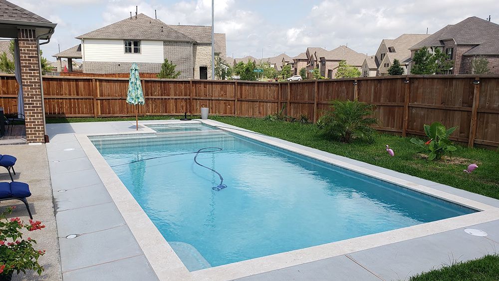 A large swimming pool in a backyard with a wooden fence surrounding it.