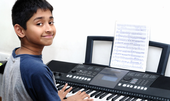 Indian boy student playing the keyboard