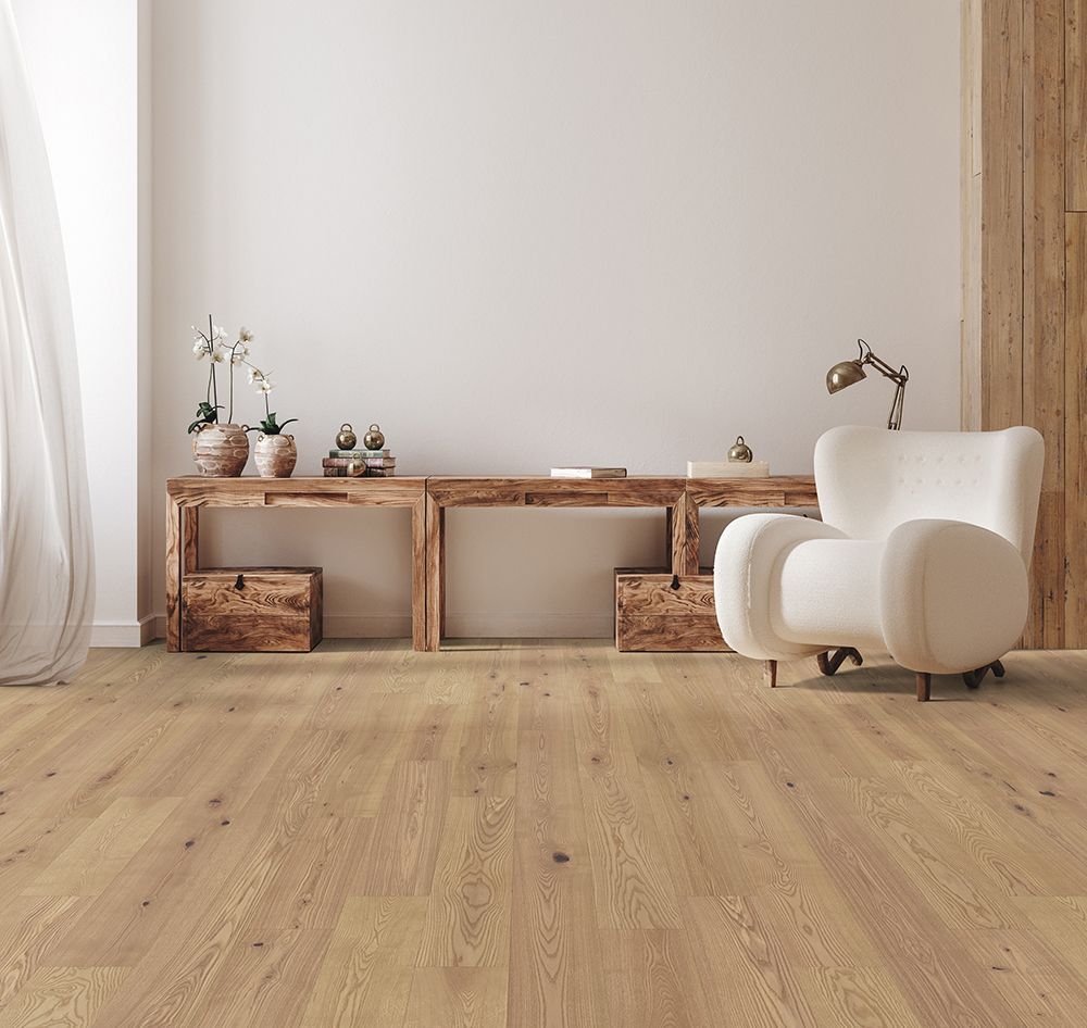 A living room with hardwood floors , a chair , a table , and a lamp.